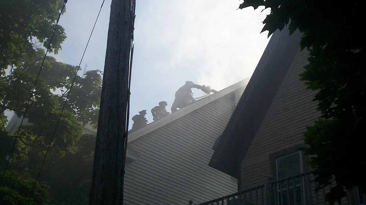 Firefighters on the roof of a smoking residential building